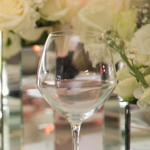 Copa de vino sobre mesa espejo con flores blancas
