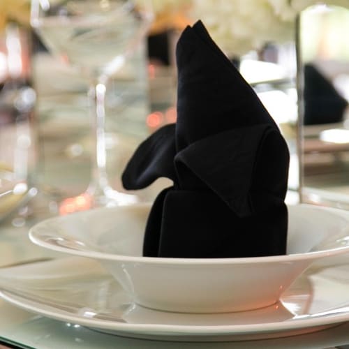 Servilleta negra doblada sobre plato blanco